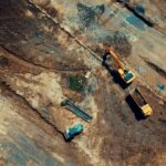 Aerial view of a construction site featuring heavy machinery and trucks, displaying industrial activity.