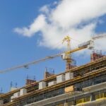 A modern construction site with cranes against a clear blue sky, showcasing urban development.
